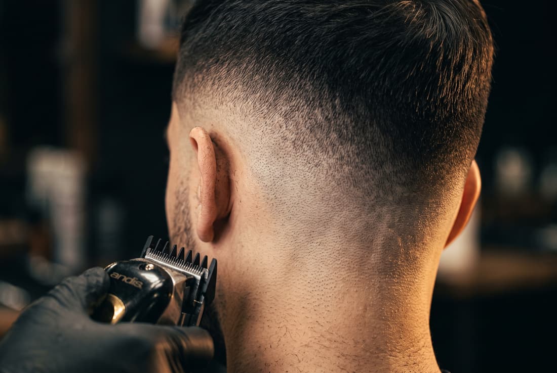 Detail skin fade střihu — přechod od holé kůže k vlasům, práce strojkem